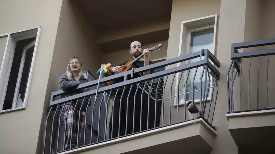 Muž hrá na gitare na balkóne svojho bytu počas hromadnej akcie, ktorú spustili v Taliansku s cieľom spojiť ľudí a zvládnuť núdzový stav kvôli novému koronavírusu 13. marca 2020 v Miláne.