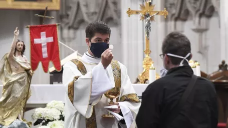 Na snímke veriaci prijíma hostiu od kňaza s ochranným rúškom počas verejnej bohoslužby v Dóme sv. Alžbety.