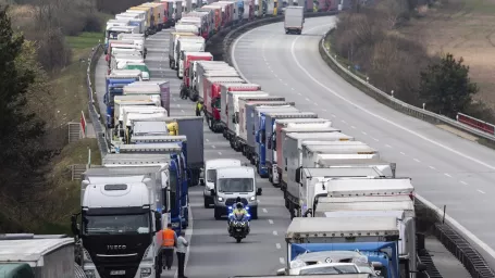 Nemeckí policajti jazdia na motorke medzi kamiónmi počas kolóny na diaľnici A4 neďaleko nemeckého Görlitzu 19. marca 2020. Obmedzenia zavedené na hraniciach s cieľom spomaliť šírenie koronavírusu v Európe spôsobili zdržania a kolóny na viacerých miestach v strednej Európe.