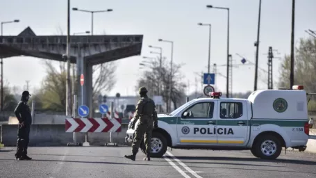 Na snímke zmiešaná hliadka tvorená policajtom a vojakom dohliadajú na slovensko-madarskom hraničnom priechode v Rajke v stredu 8. apríla 2020 v Bratislave.