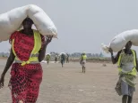 Sudánske ženy kráčajú s vrecmi potravinovej pomoci počas distribúcie ICRC v regióne Leer v Južnom Sudáne