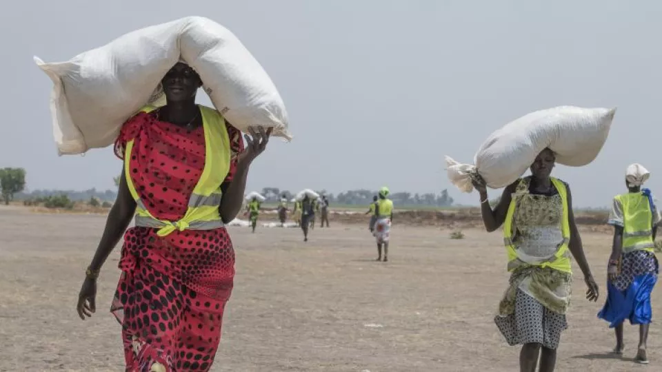 Sudánske ženy kráčajú s vrecmi potravinovej pomoci počas distribúcie ICRC v regióne Leer v Južnom Sudáne