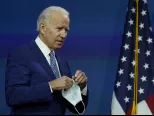 Novozvolený americký prezident Joe Biden s ochranným rúškom v ruke  prichádza k rečníckemu pultu vo Wilmingtone v pondelok 9. novembra 2020.