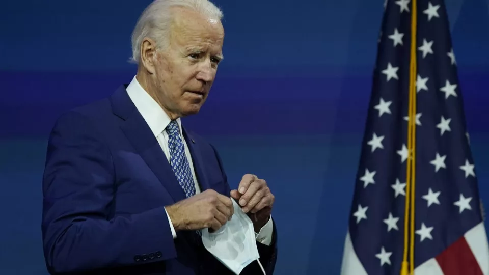 Novozvolený americký prezident Joe Biden s ochranným rúškom v ruke  prichádza k rečníckemu pultu vo Wilmingtone v pondelok 9. novembra 2020.