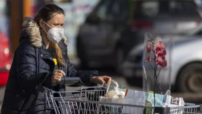 Na snímke žena s respirátorom vychádza z potravín