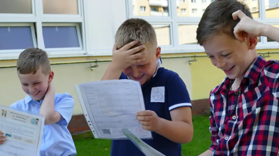 Žiaci tretieho ročníka ZŠ Karpatská v Žiline počas prezerania vysvedčenia pred školou.