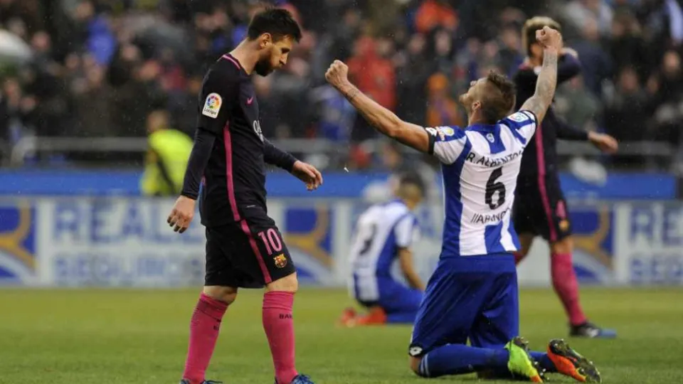 Futbalista Barcelony Lionel Messi (vľavo) kráča okolo radujúceho sa hráča Deportiva Raula Albentosu po výhre Deportiva nad Barcelonou 2:1.